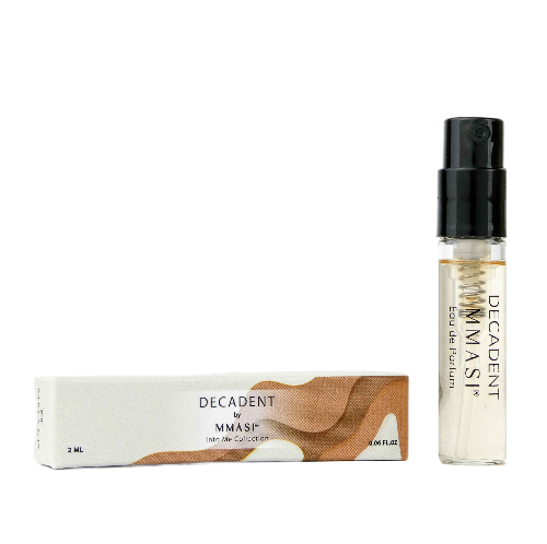 A small perfume bottle labeled "Decadent by MMASI" next to its white and brown packaging box on a transparent background
