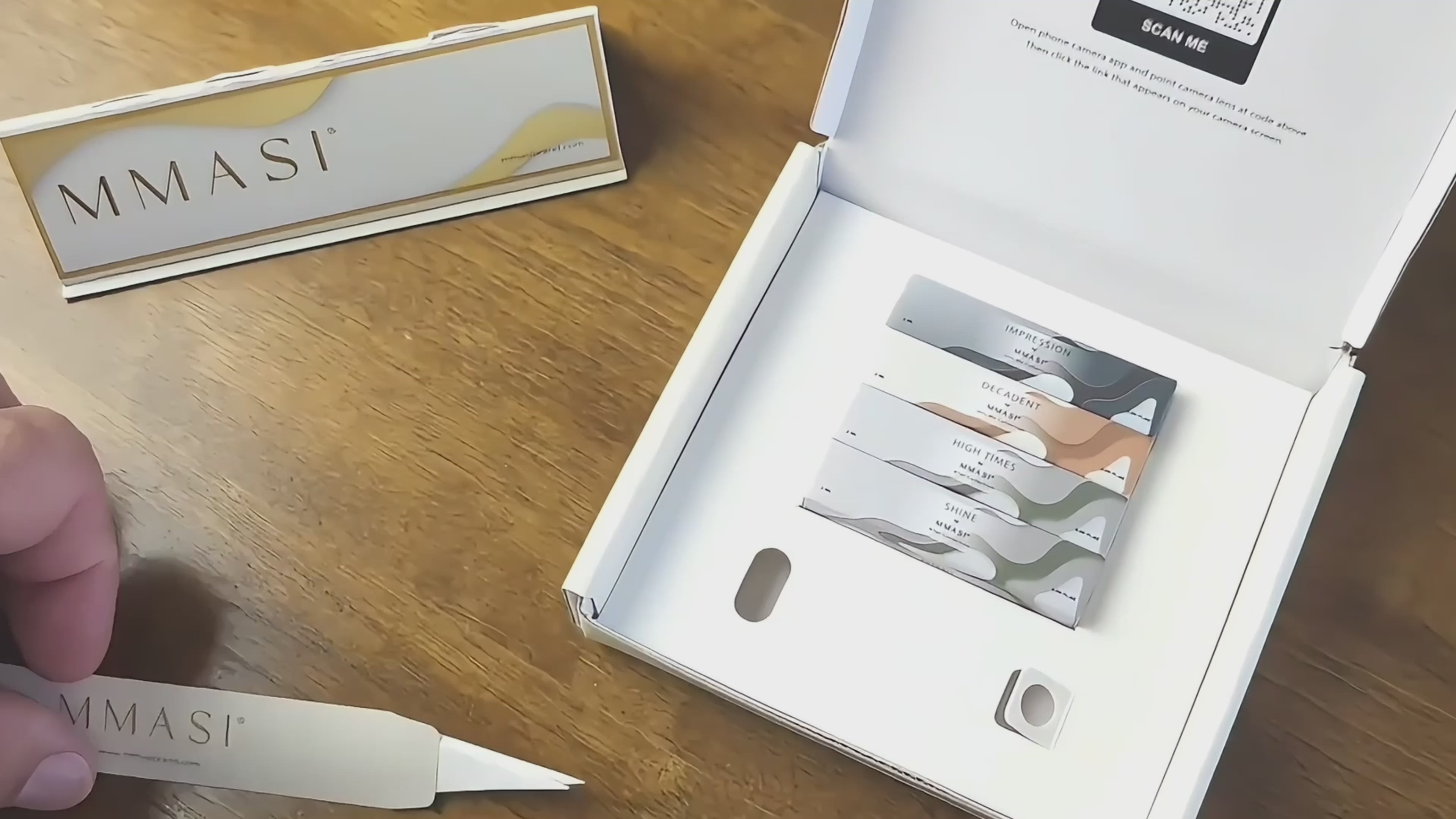 Hands of a man opening a discovery set box with four perfume samples. He opens one vial and sprays it on a scent strip then showcases half his face smelling the perfume. Then he places all the scent strips on a scent strip holder labeled MMASI