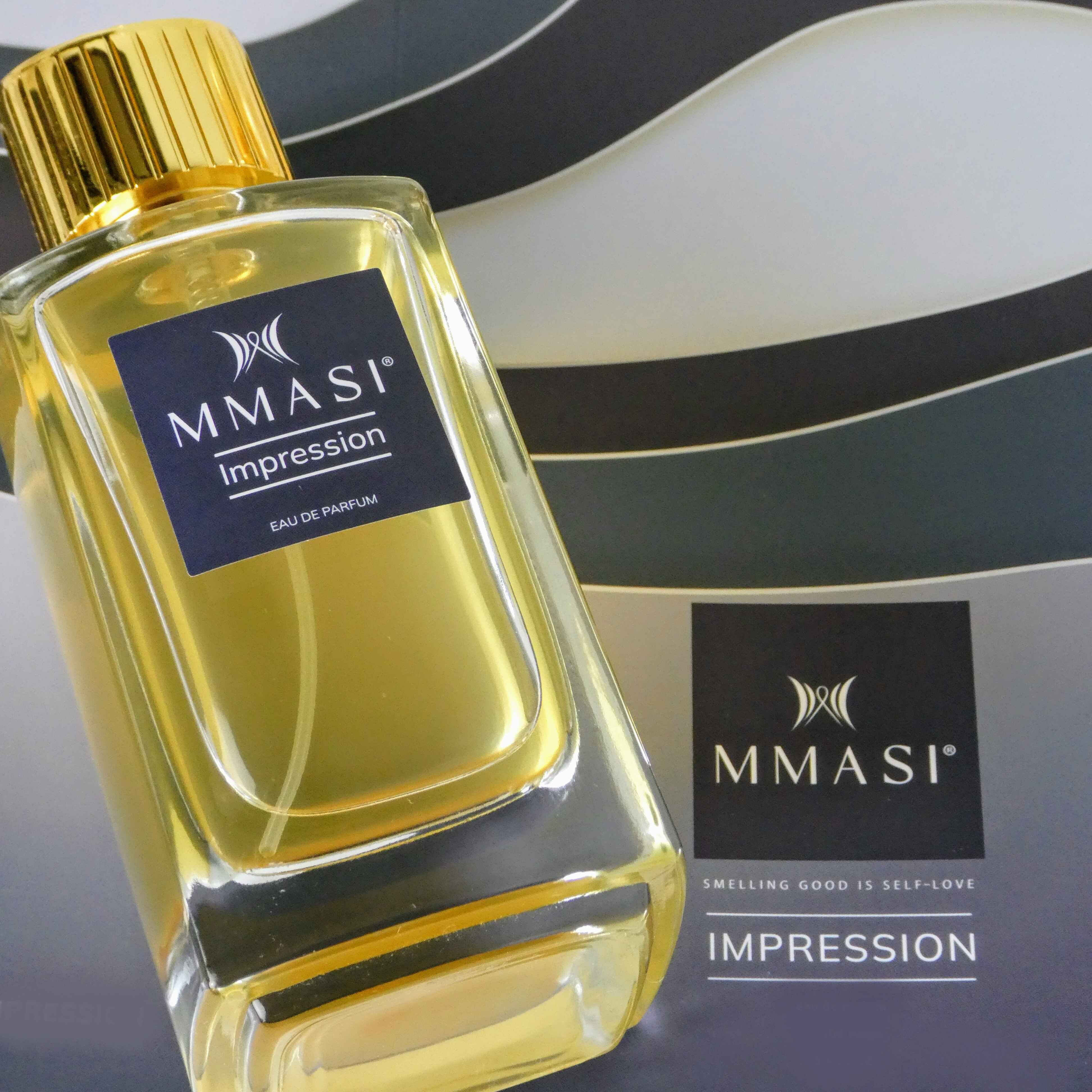 A close-up photo of a rectangular glass perfume bottle with a gold cap, labeled MMASI Impression Eau de Parfum, against a backdrop of a blue and white wavy pattern with the MMASI logo and the tagline "Smelling good is self-love".